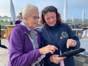 Zwei Pilotinnen schauen gemeinsam auf ein Tablet auf der Terrasse am Flugplatz