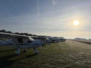 Reihe von Flugzeugen auf der Graspiste im Morgenlicht