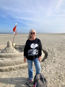 Pilotin am Nordseestrand neben einer Sandburg
